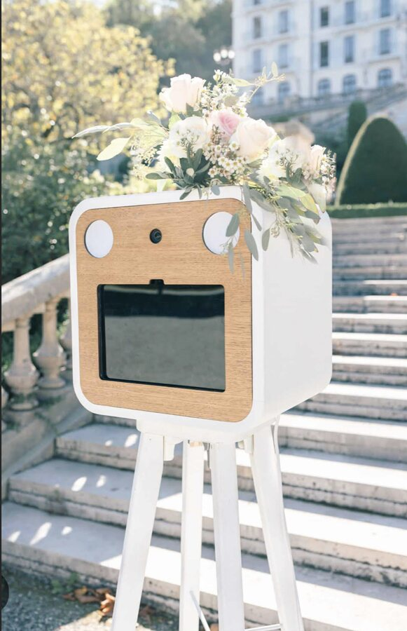Photomaton en bois et blanc décoré de fleurs installé en extérieur pour un événement à Blois